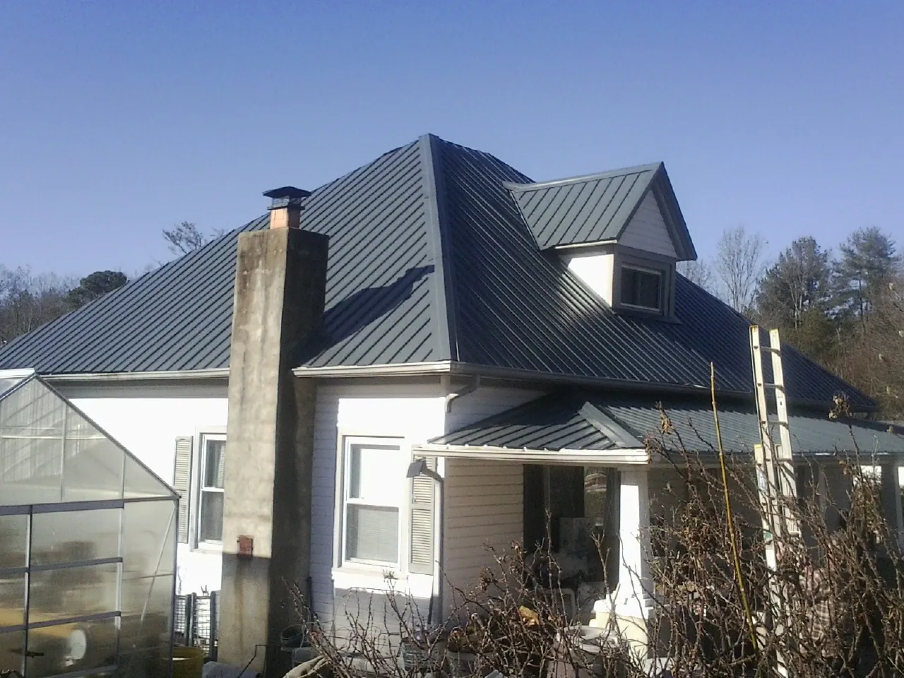 Dark blue standing seam metal roof on a white farmhouse with dormer — Slate & Tile Roof Repair by Roofing Brothers in Camp Hill