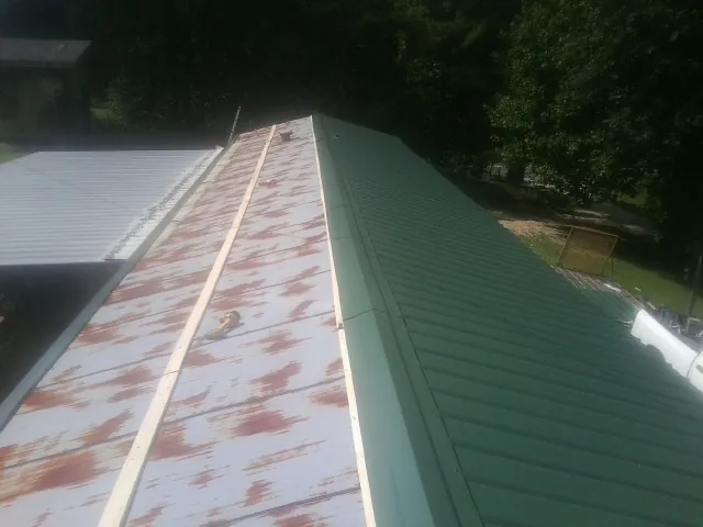 Old rusted panels beside newly installed green metal roofing — Wind Damage Roof Repair by Roofing Brothers in Camp Hill