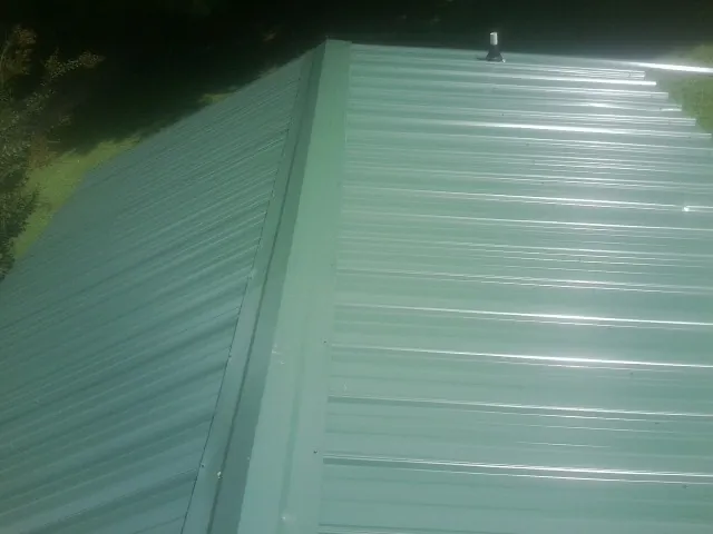 New green metal panels meeting at the ridge of a roof — Flat Roof Repair work by our crew in Camp Hill