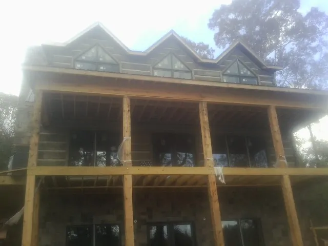 Dormers and porch framing on a large log home under construction — Roof Coating work by our crew in Camp Hill