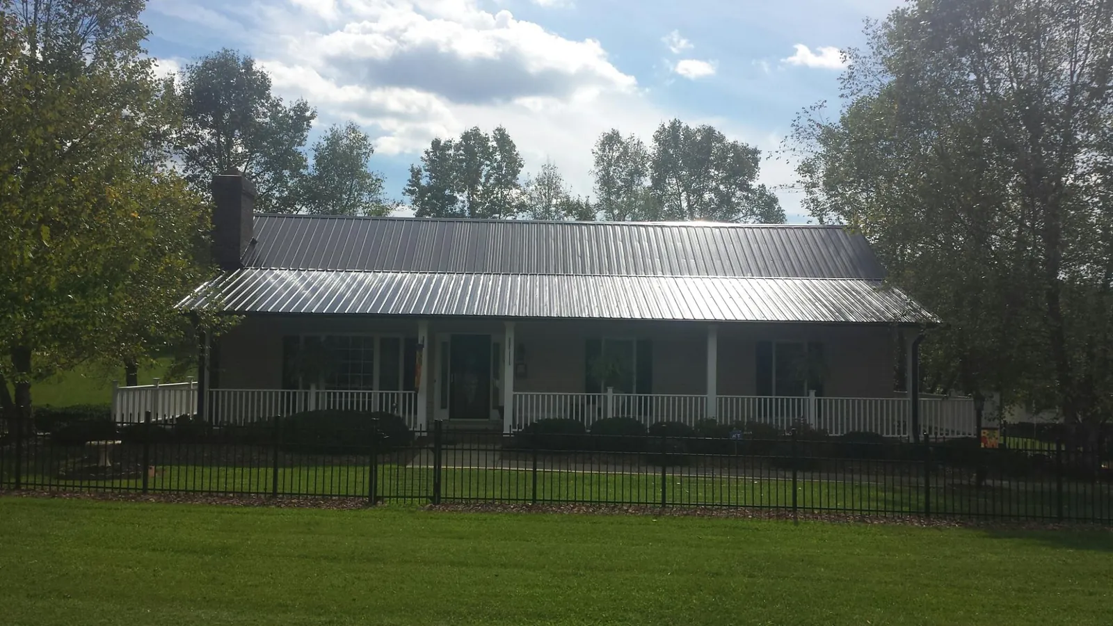 Gray metal roof on a brick ranch with a full width front porch — Gutter Guard Installation work by our crew in Camp Hill