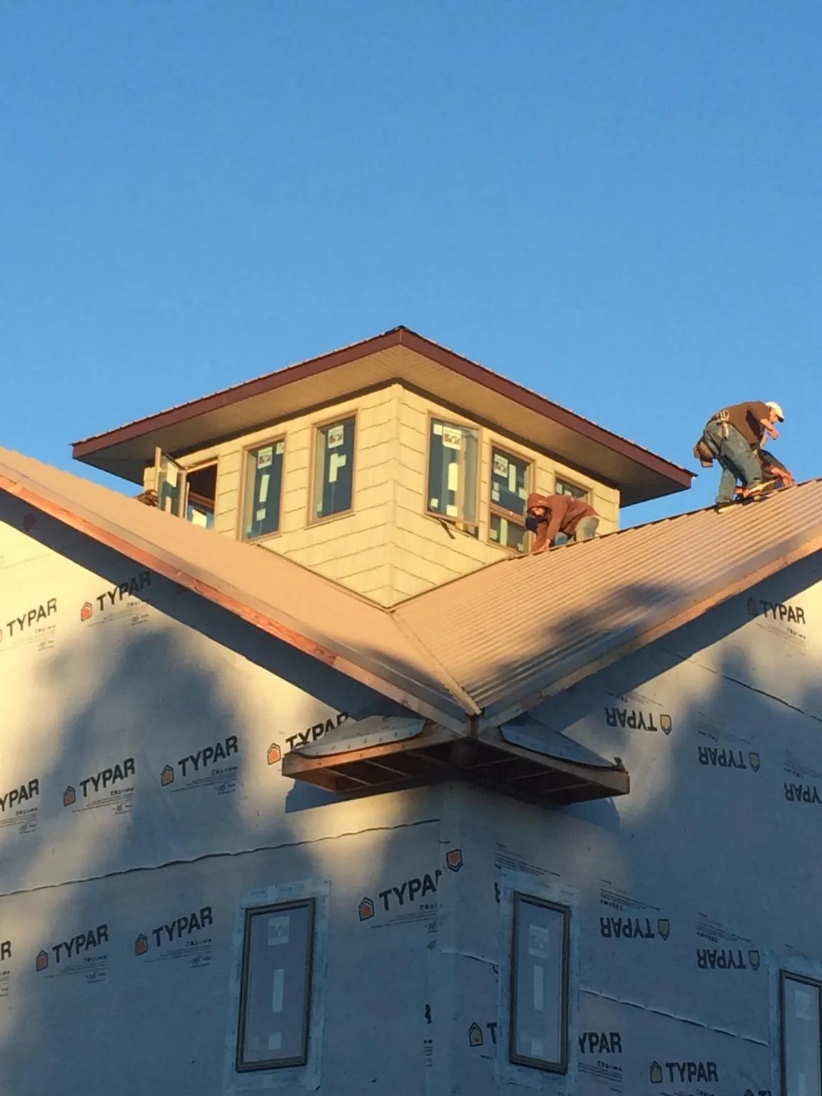 Roofers working around a rooftop cupola on a new metal roof at sunset — Roof Waterproofing in Camp Hill by Roofing Brothers